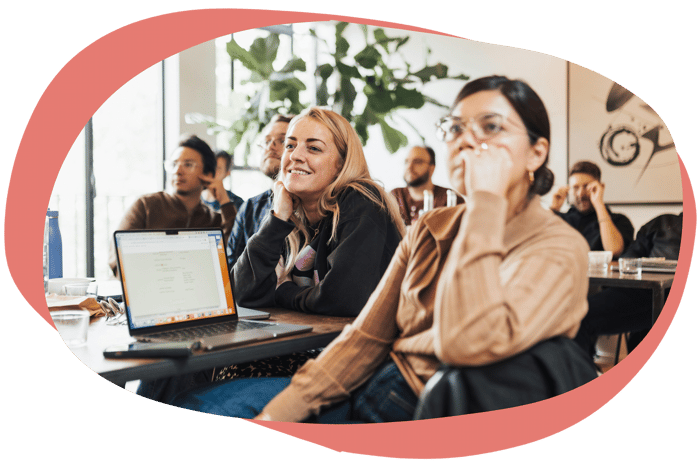 A group of people engaged and smiling during a training session A group of people engaged and smiling during a training session