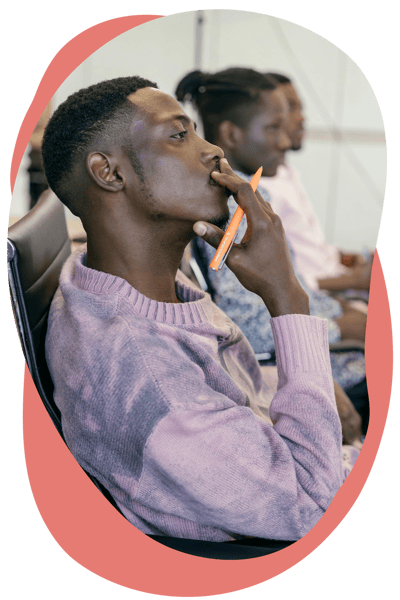 A person in a purple jumper looking thoughtful and holding a pen A person in a purple jumper looking thoughtful and holding a pen