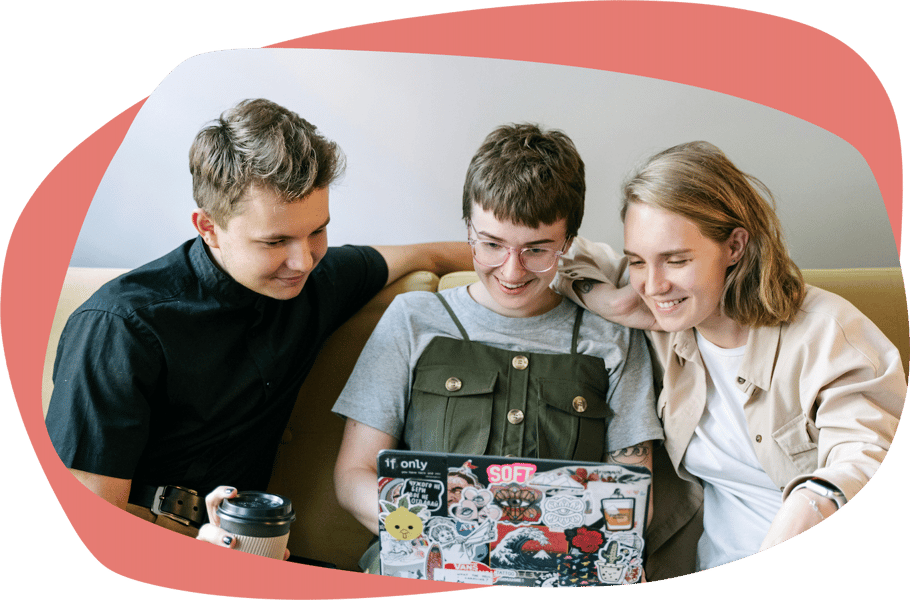 Three people sat on a sofa looking at a laptop and smiling Three people sat on a sofa looking at a laptop and smiling