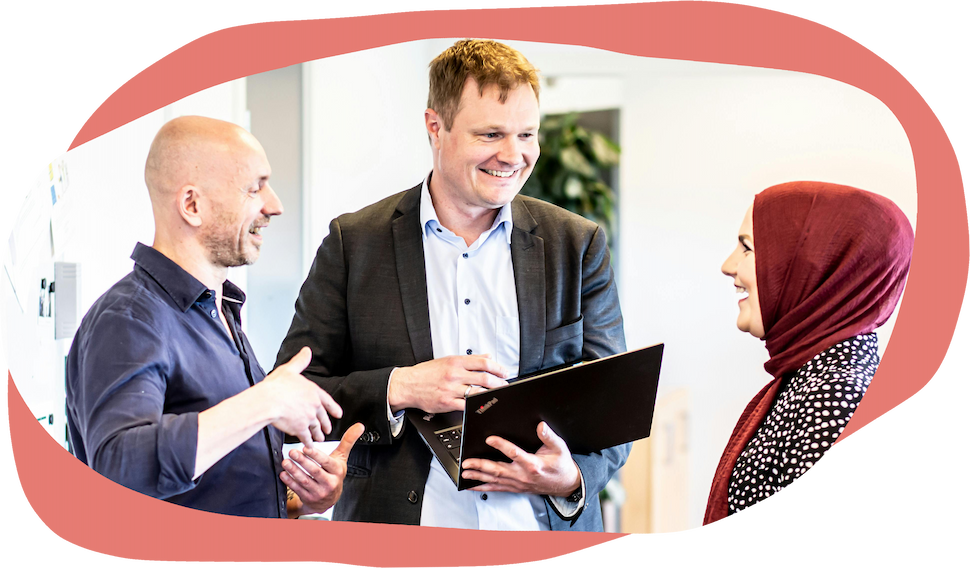 Three people standing together in a work environment smiling
