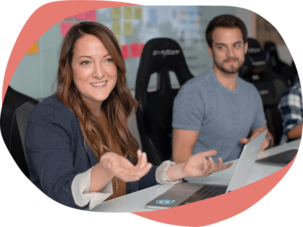Two people sat at a desk with laptops and sticky notes Two people sat at a desk with laptops and sticky notes