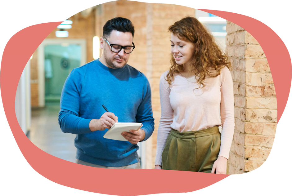 Two people standing in a hallway reviewing notes Two people standing in a hallway reviewing notes