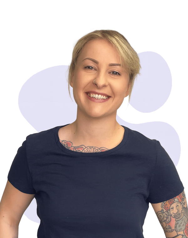 Jess: A person with light hair tied back, smiling warmly. They are wearing a navy T-shirt and have visible tattoos on their arms and chest. Jess: A person with light hair tied back, smiling warmly. They are wearing a navy T-shirt and have visible tattoos on their arms and chest.